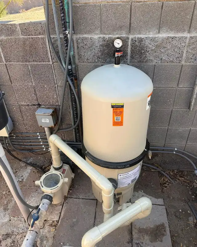 DE filter tank and pump plumbed against a block wall