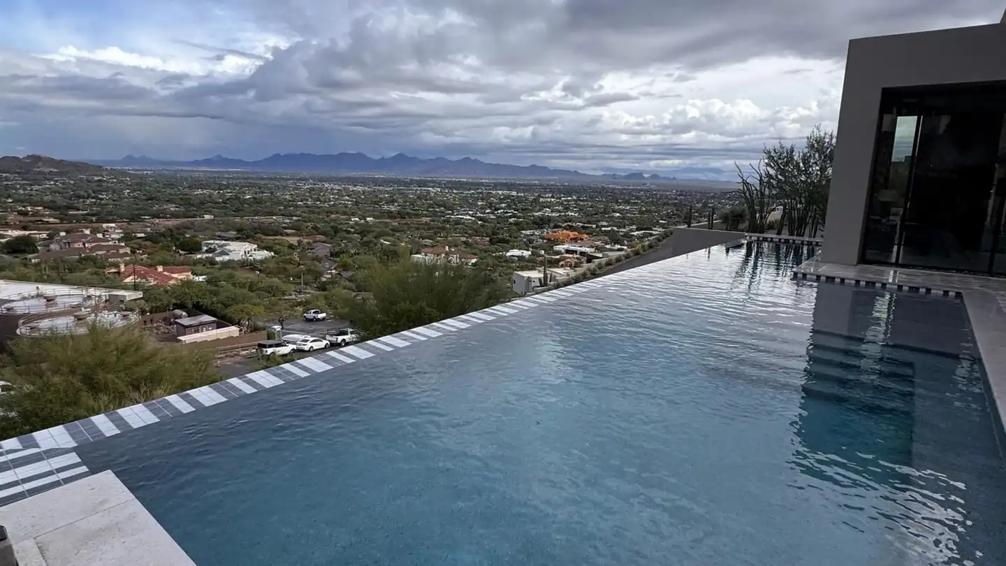 Vanishing-edge pool under monsoon storm clouds, the North Valley spread out below